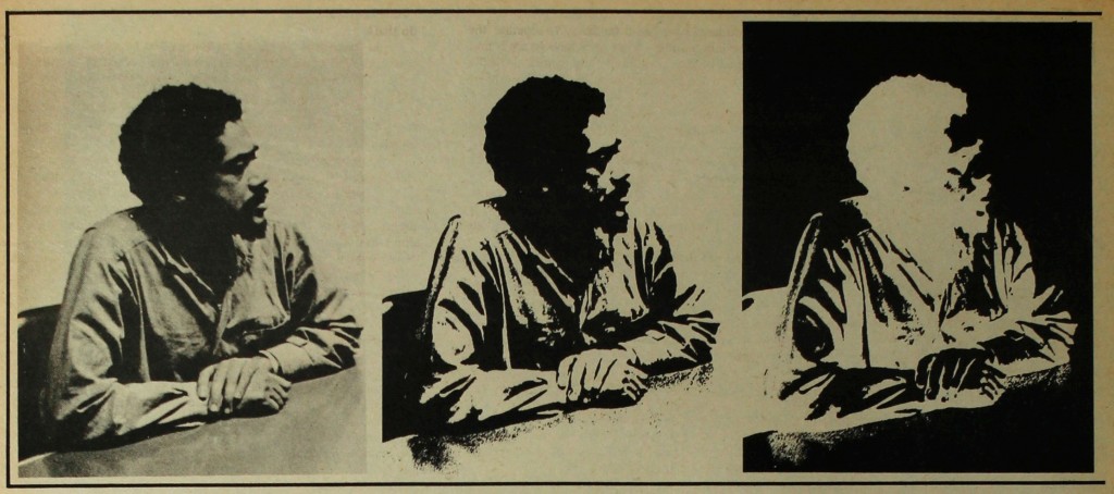 A photo of Bobby Seale sitting at a table. His hands are resting on the table and he is looking to the right.