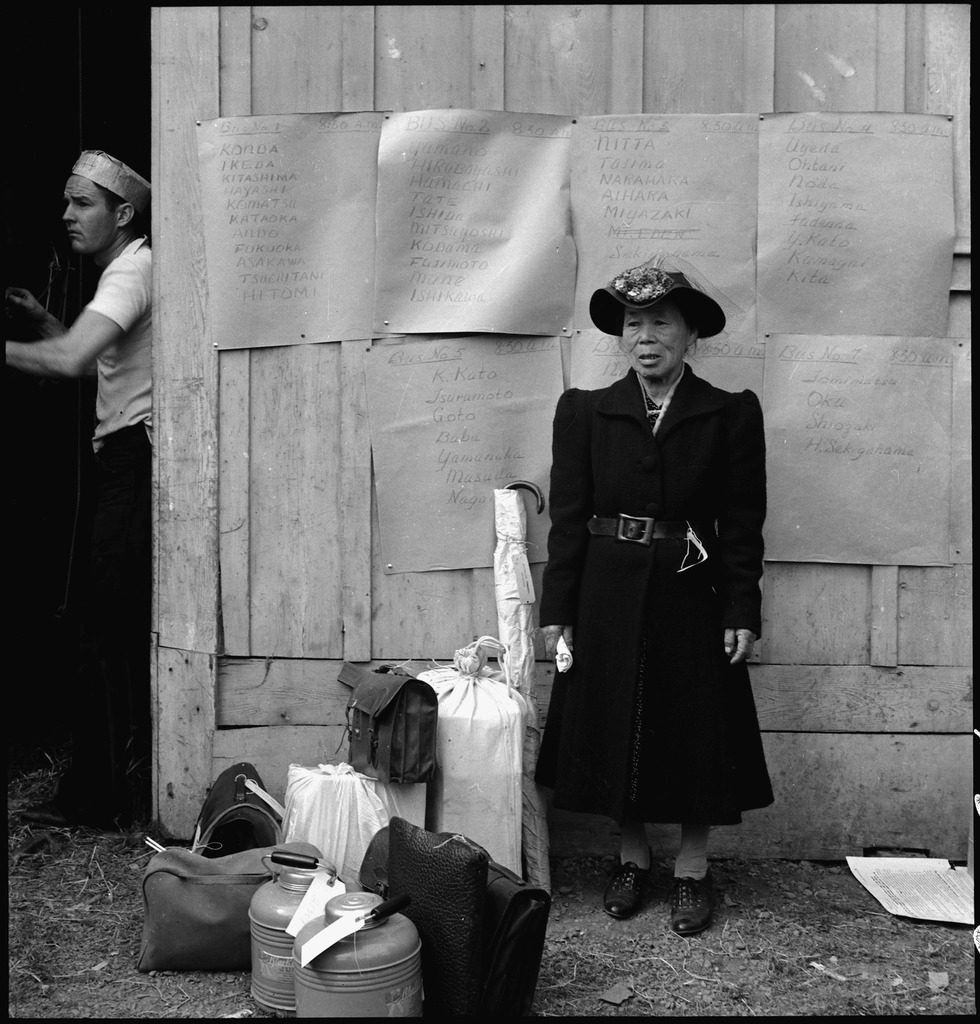 May 9, 1942. Centerville, California. Original caption: This evacuee stands by her baggage as she waits for evacuation bus. 