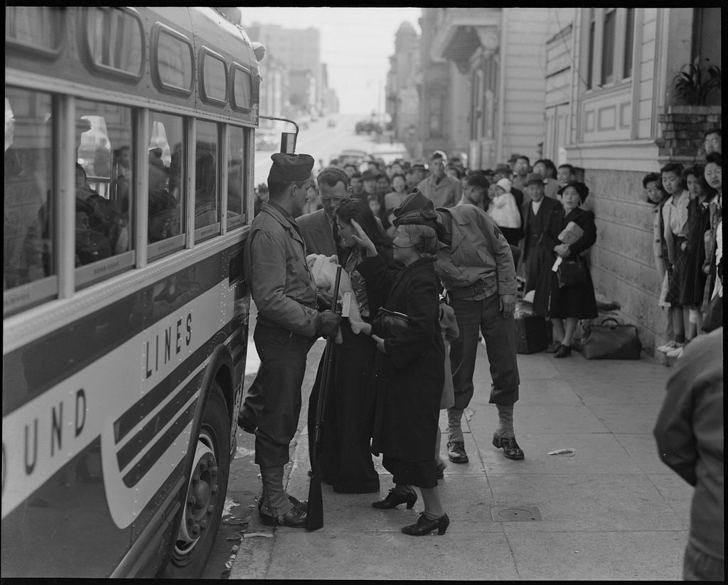 April 19, 1942, San Francisco. Original caption: Friends and neighbors congregate to bid farewell, though not for long, to their friends who are enroute to the Tanforan Assembly center. They, themselves will be evacuated within three days.