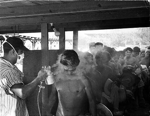 Braceros being sprayed with DDT at a processing center.