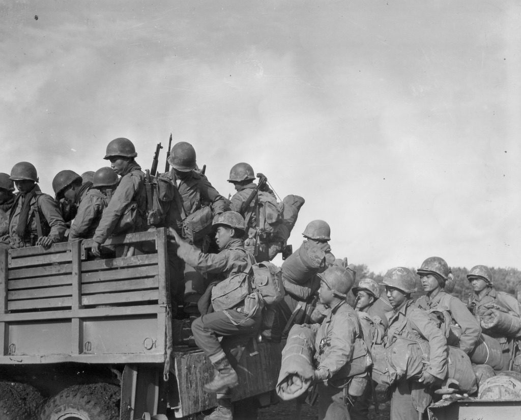 Japanese American troops climb into the back of a truck.