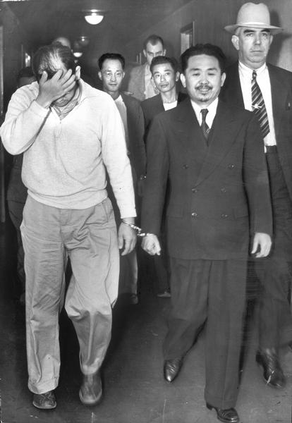 Masaru Kuwada and Ernest Kinzo Wakayama being escorted to cells by US Marshalls after being arraigned on charges of conspiring to violate exclusion orders against Japanese Americans during World War Two.