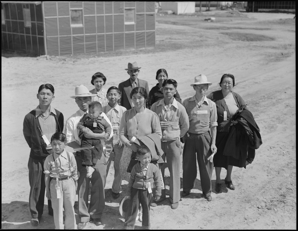 Members of the Esaki family standing on a dusty road next to barracks at Turlock assembly center.