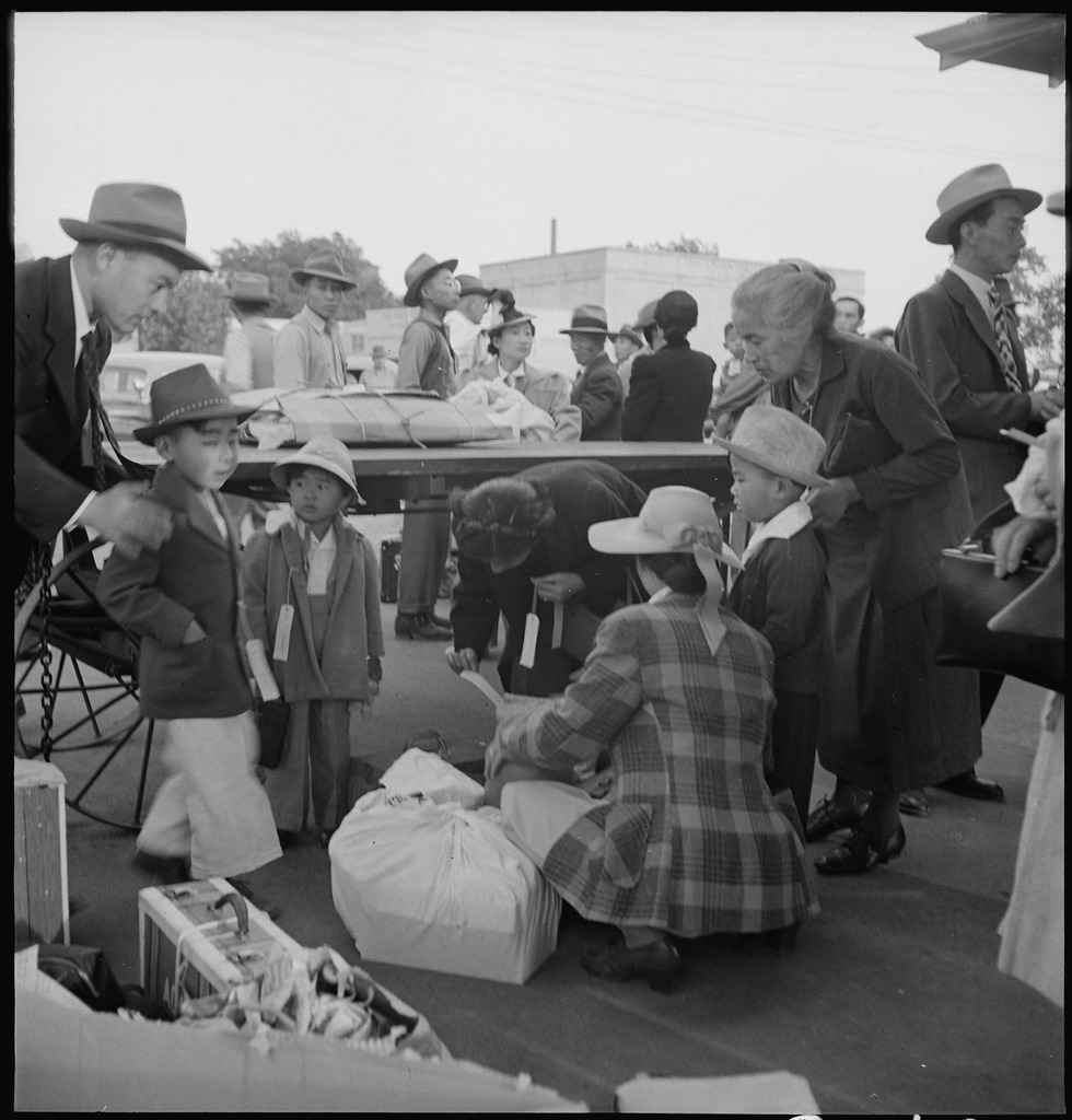 Families of Japanese ancestry with their baggage at railroad station awaiting arrival of special train which will take them from their home town of Woodland, California to the Merced Assembly center