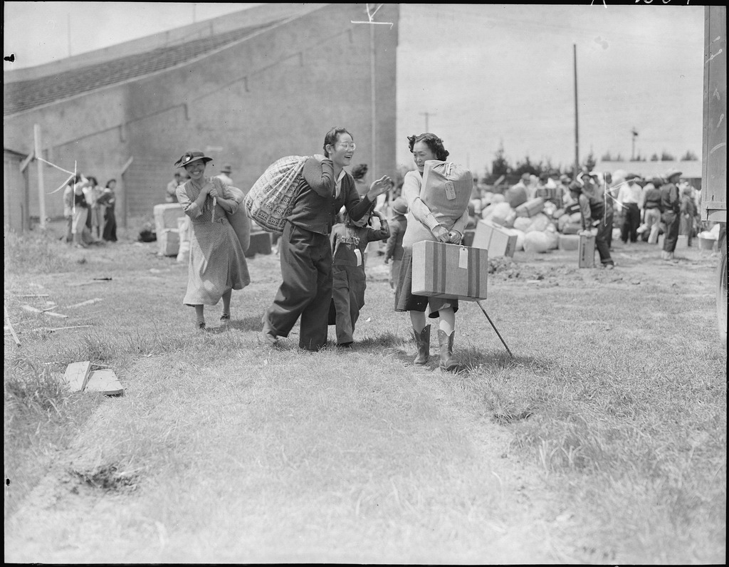 Two families carrying their luggage shortly after arriving at the Salinas rodeo grounds, which was converted to an assembly center.