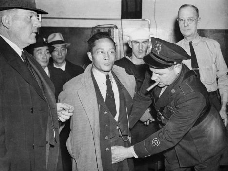 Japanese American man being searched by a police officer.