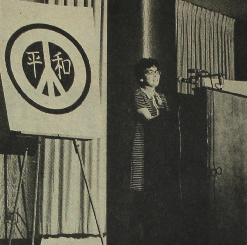 Kiku Uno standing at a podium and speaking into a microphone at an anti-war event in Los Angeles in 1971.