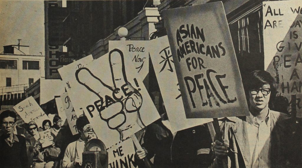 Asian American protesters marching through Little Tokyo in a protest against the Vietnam War in1970. A young man in the front is holding a sign that reads "Asian Americans for Peace."