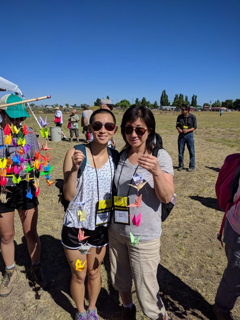 Sara and their mother at the 2018 Tule Lake Pilgrimage holding strands of origami cranes