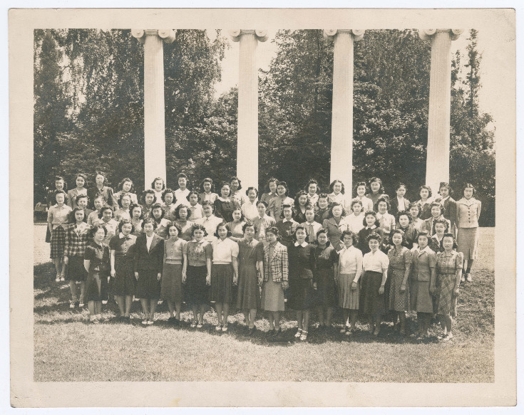 Group photo of Japanese American young women posing in front of columns on the University of Washington column.