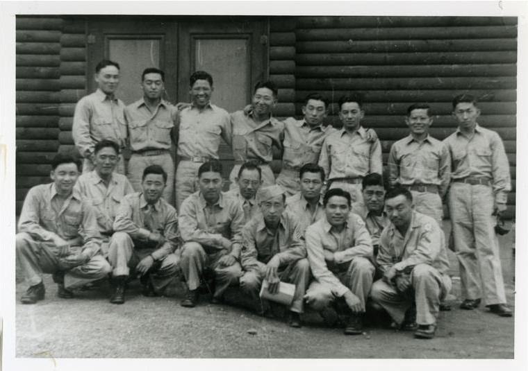 Black and white photo of Japanese Americans at the Military Intelligence Language School during WWII. The men are wearing khaki uniforms and posing in two rows, those in the front row kneeling and those in the back standing. 