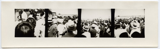 Black and white panoramic photo of a crowd of Japanese Americans watching people board buses to leave Heart Mountain.