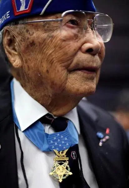 Close-up photo of Joe Sakato wearing a suit with a 442nd garrison cap and a Congressional Medal of Honor.