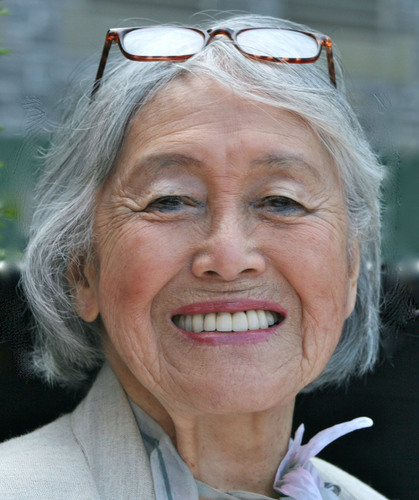 Setsuko Matsunaga Nishi from the shoulders up. She is smiling and wearing a cream colored blazer and white and pink scarf.