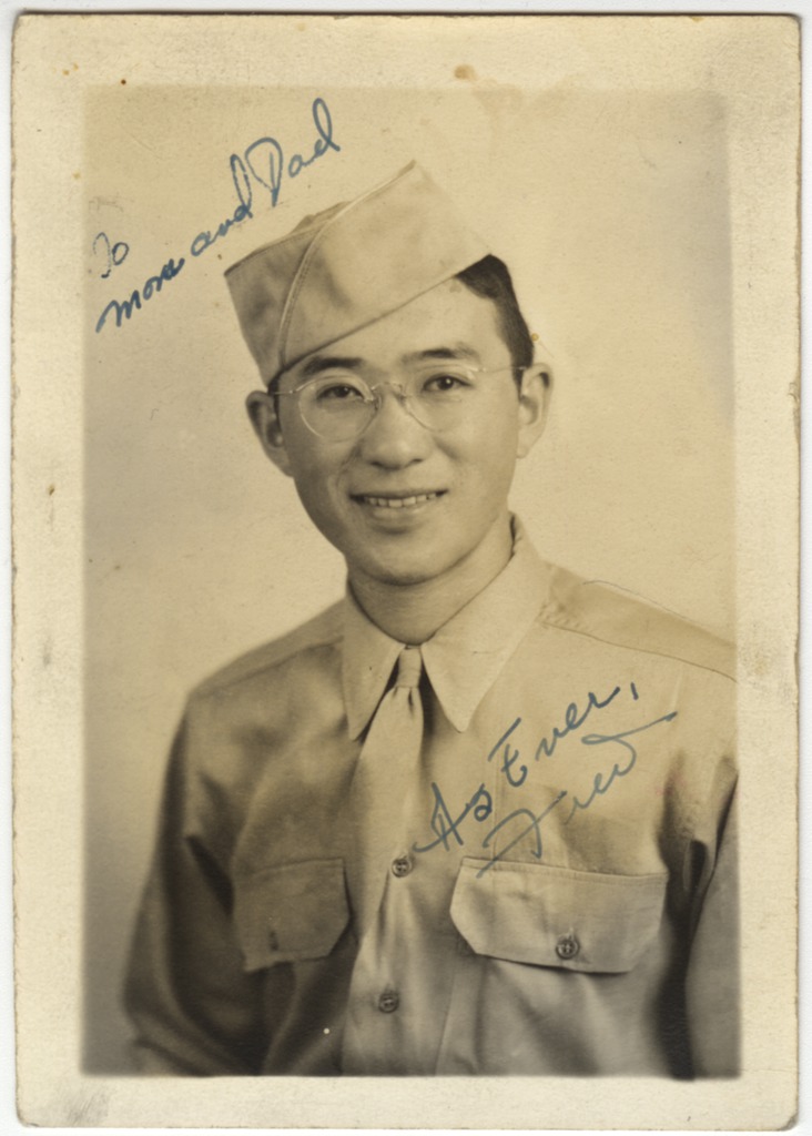 Portrait of Fred Shiosaki wearing a U.S. Army uniform, cap and glasses. He is smiling at the camera. "To mom and dad, as ever, Fred" is written on the photo.