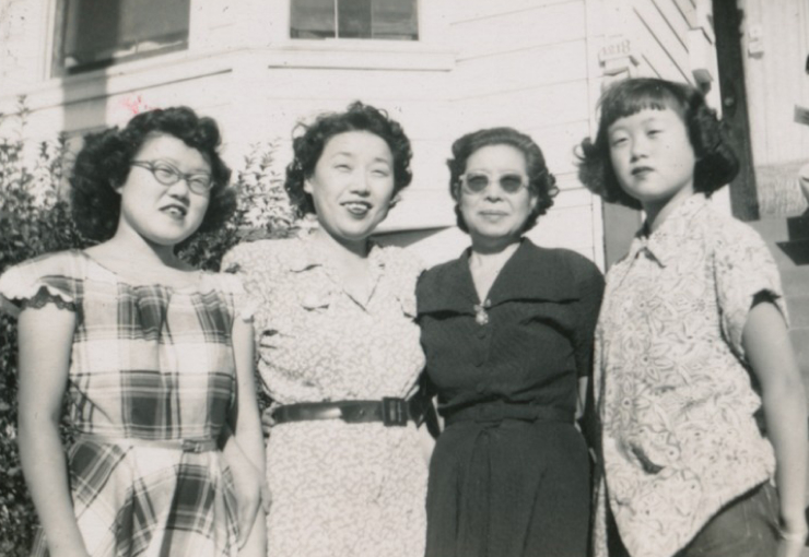 Four Japanese American women in the 1940s stand together and pose for a photo.