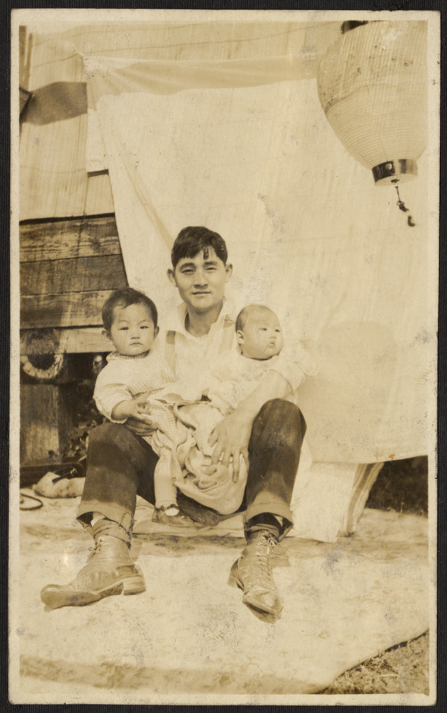  A man holds two babies in his arms, c. 1930.