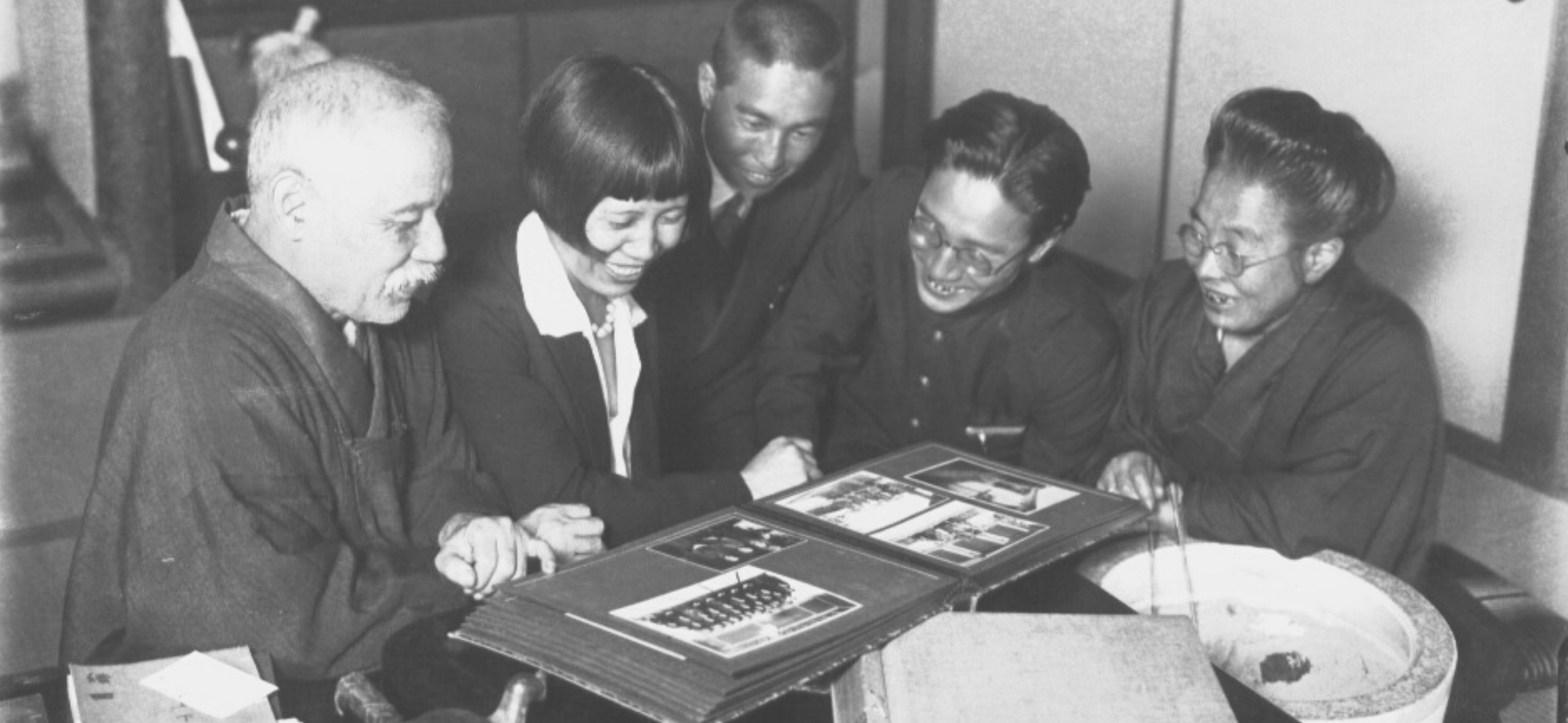 Japanese family huddles together looking at a photo album.