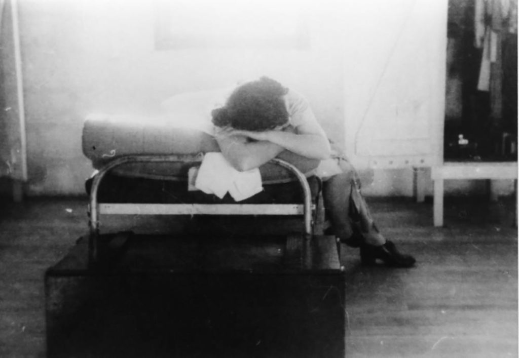 A young incarceree resting on a cot in a barrack of the Manzanar Children’s Village