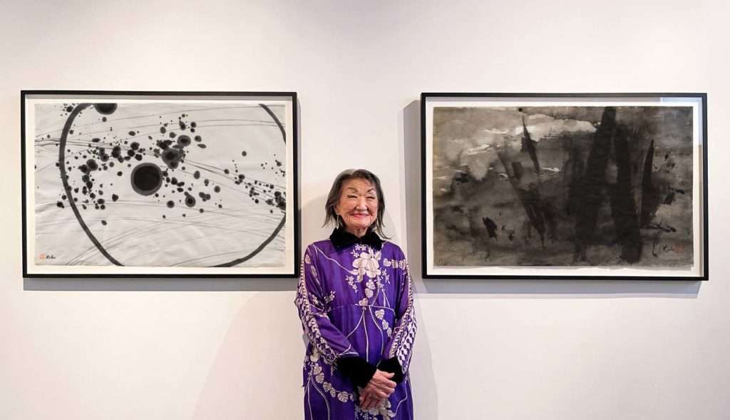 Artist Koho Yamamoto standing between two pieces on display at her 2021 solo exhibition.
