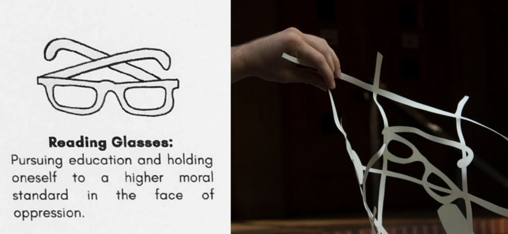 A sketch of a pair of reading glasses next to a paper cut out of the glasses in a memory net. A written description says, "Reading glasses: Pursuing education and holding oneself to a higher moral standard in the face of oppression."