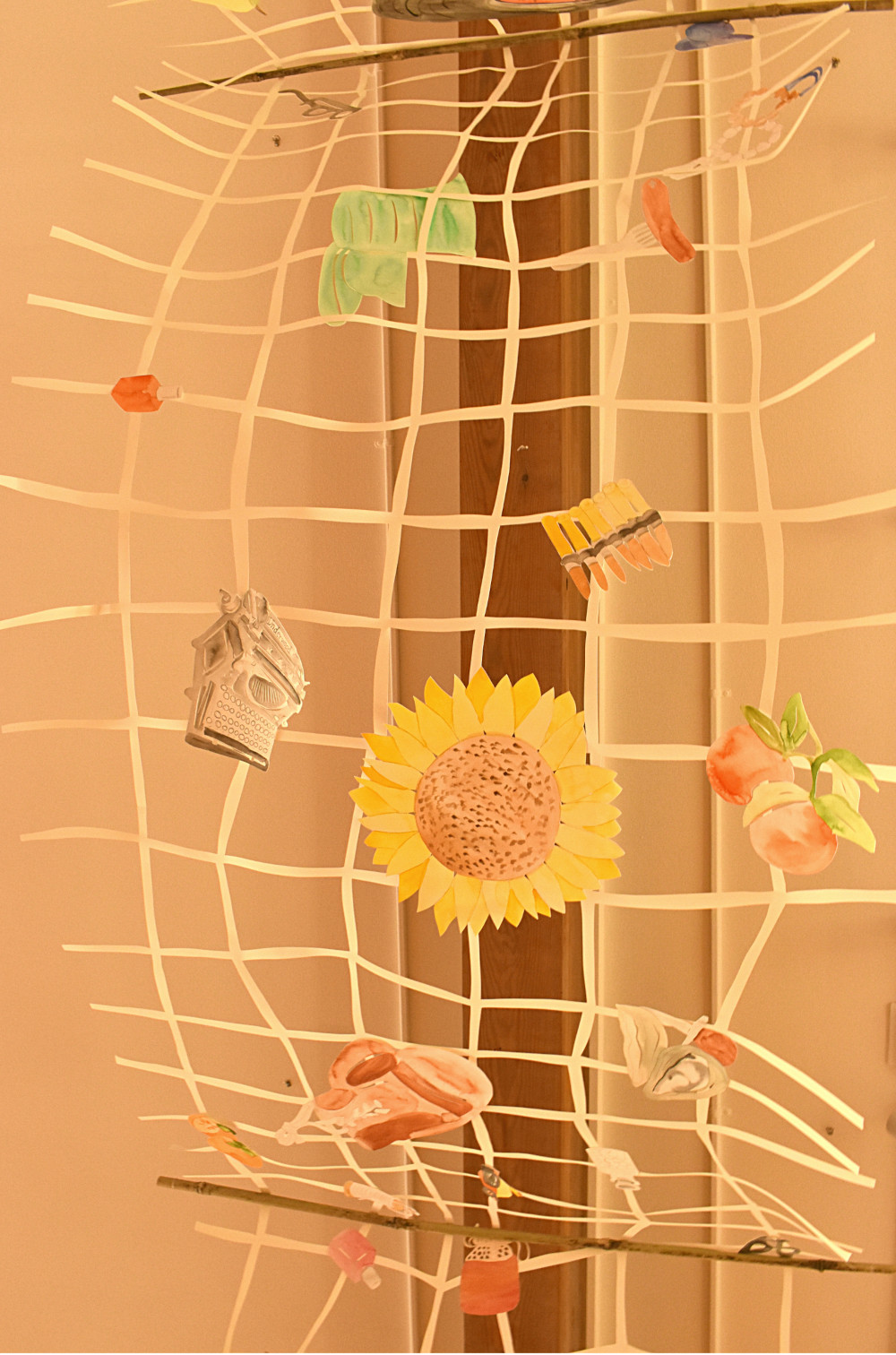 A section of Lauren Iida's memory net. Objects shown include Buddhist prayer beads, a hotdog on a fork, machine gun bullets, a bottle of nail polish, a typewriter, a sunflower, boxing gloves, and fruit.