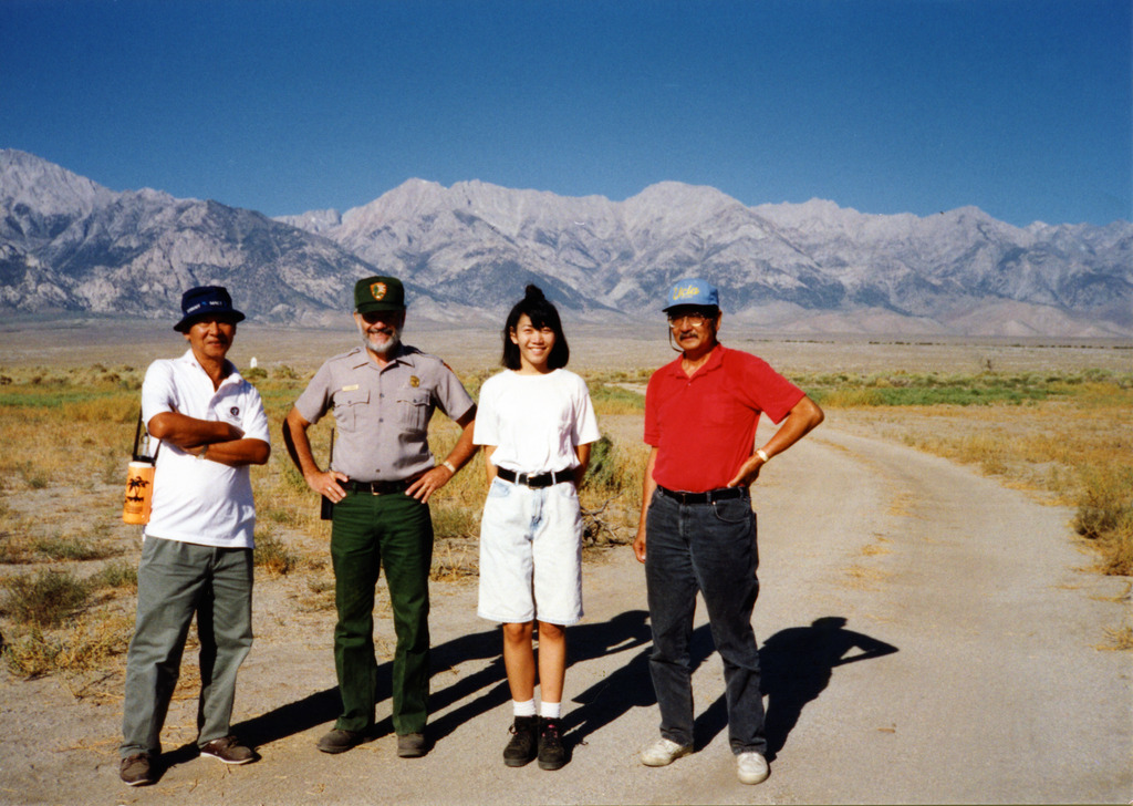 A young woman and two older men with a park ranger at the Manzanar National Historic Site.