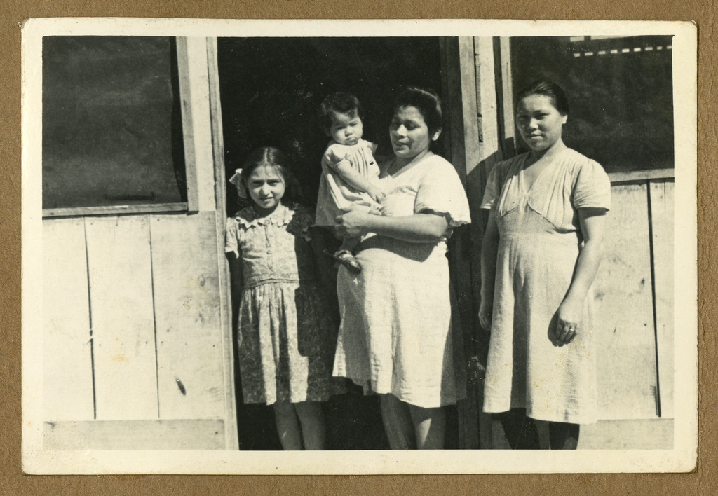 Two women with an older child and a baby in a doorway. One woman and the older child appear to be Peruvian and the other woman and baby appear to be Japanese.