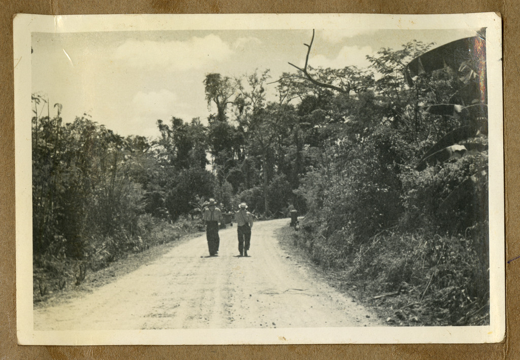 Two Japanese Peruvian workers walking down a dirt road in a plantation.