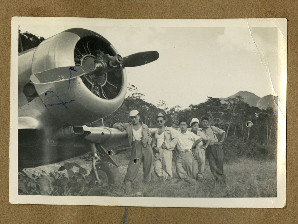Five Japanese Peruvian men posing next to an aircraft in a field.