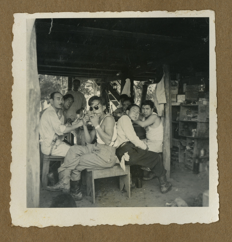 Japanese Peruvian plantation workers gathered around a table sharing a meal.