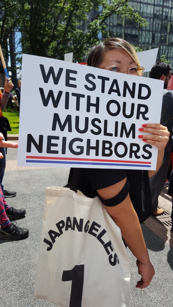 Danielle at a protest holding a sign that reads "We stand with our Muslim neighbors"