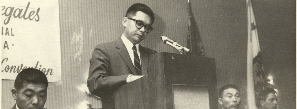 Norm Mineta speaking at a podium