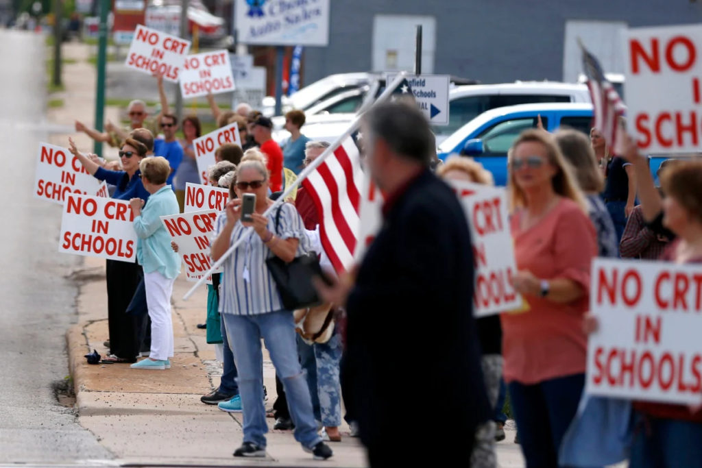 White parents holding American flags and signs that read "No CRT in schools."