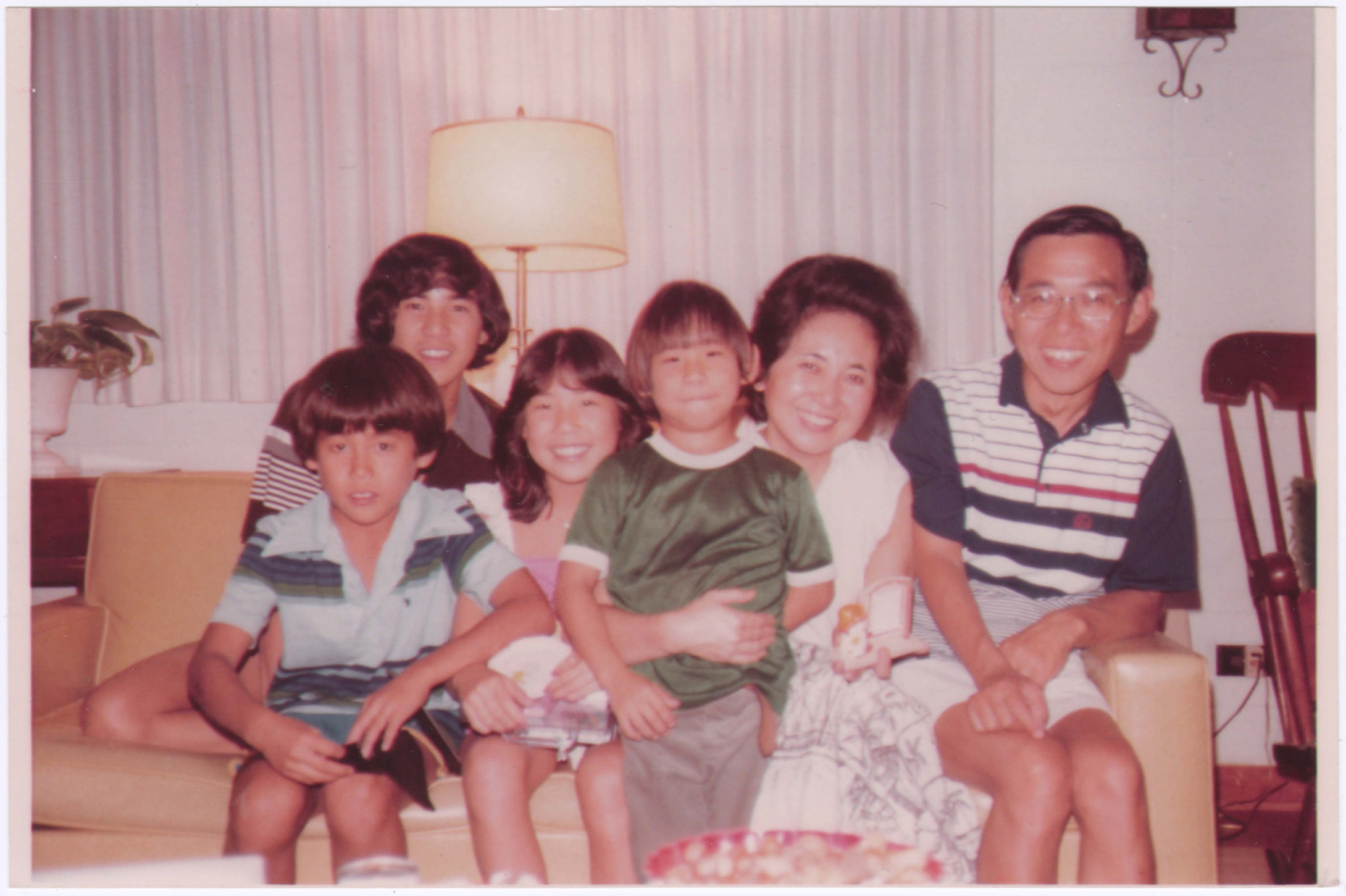 The Miwa family sitting on a couch and smiling, circa 1970s.