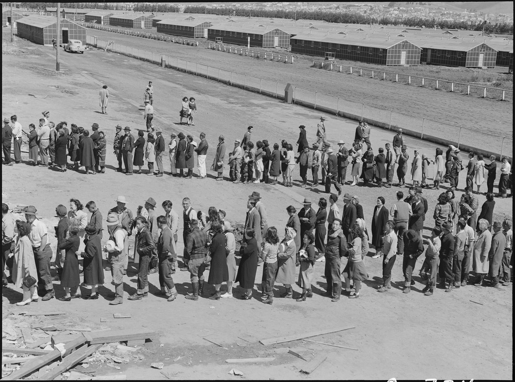 Japanese Americans standing in two long lines outside the mess hall in the Tanforan Assembly Center.