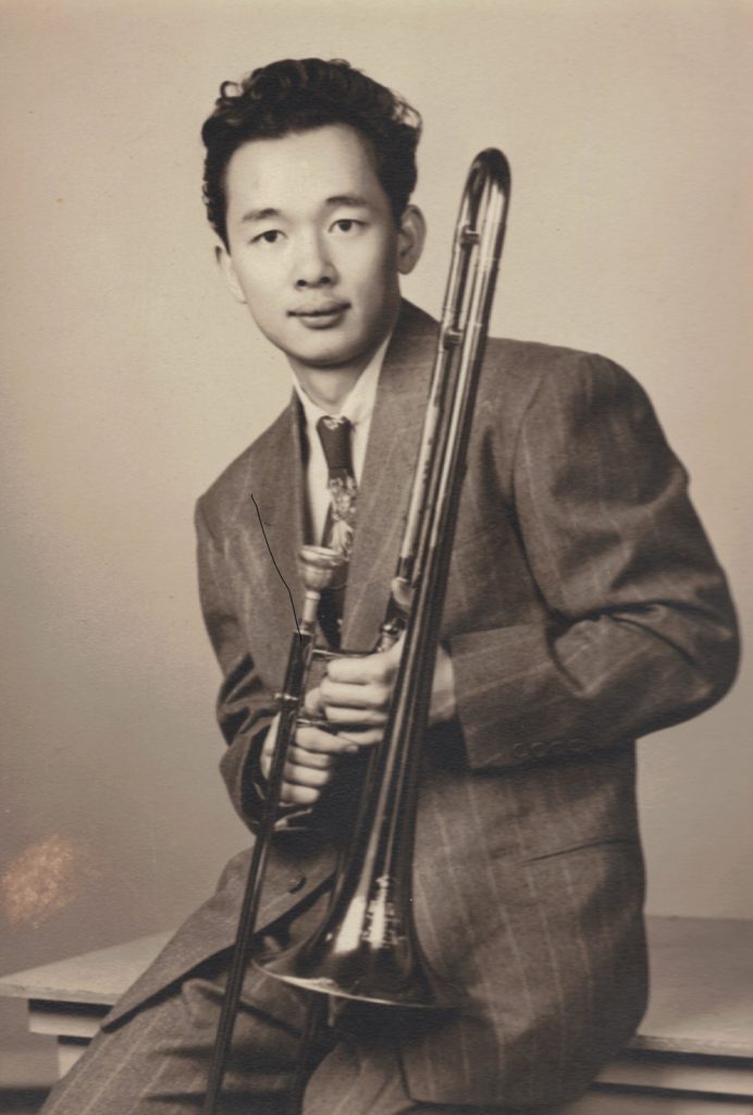 Harry Kitano wearing a suit and posing with a trombone, circa 1940s.