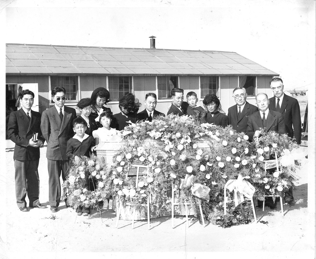 Mourners standing next to a casket at a funeral in Amache concentration camp
