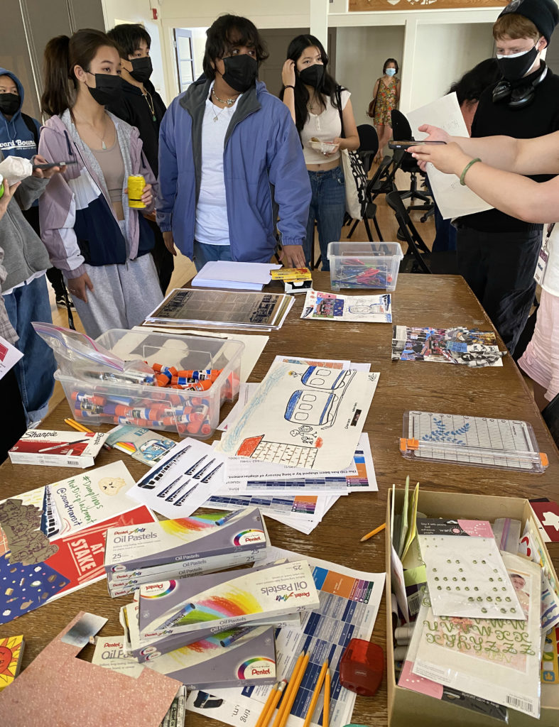 Students standing around a table with art supplies.