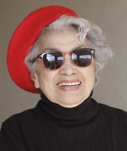 Mitsuye Yamada smiling in sunglasses, a bright red beret and a black turtleneck.