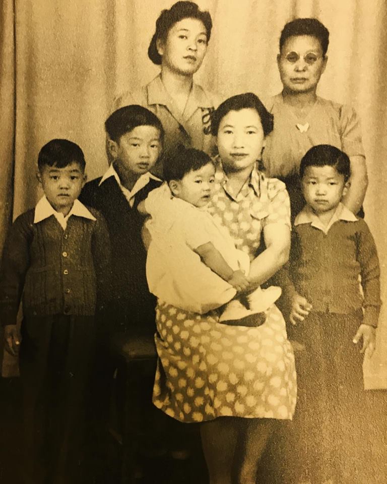 Itsuye and Mitsuki Tsuchida posing for a family portrait with three young children and two women inside Topaz concentration camp.
