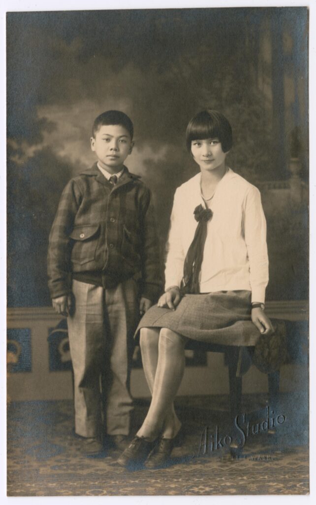 Portrait of Mary and Tsutomu Fukuyama as children. Mary is seated on a chair while Tsutomu stands next to her.