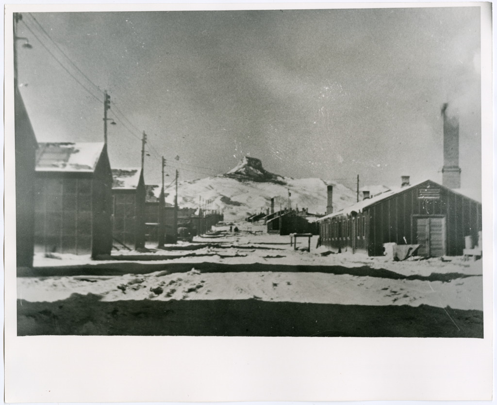 Concentration camp barracks covered in snow with Heart Mountain visible in the distance.