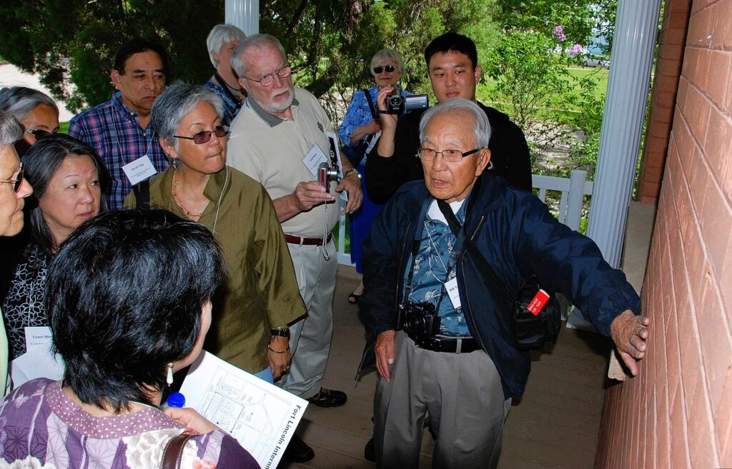 Attendees at UTTC's 2010 Fort Lincoln Planning Conference gather around internee survivor Bill Nishimura during a tour of a barracks building