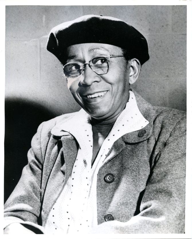 Portrait of Erna P. Harris circa 1970s. She is smiling and wearing glasses and a black beret.