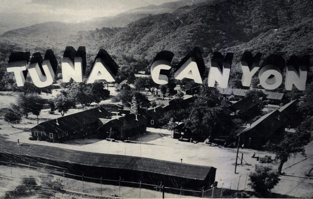 Model of Tuna Canyon Detention Facility with barracks and a sign in the hills behind the camp that reads 