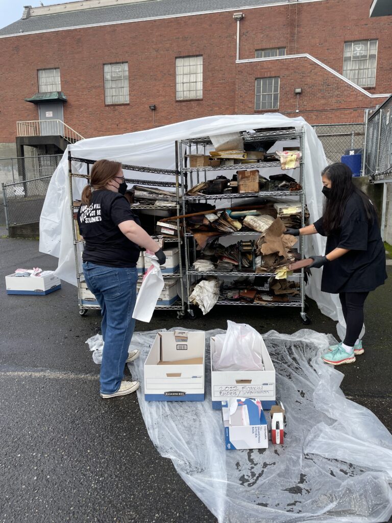 Two members of Densho's archives team work to salvage materials from the Betsuin's archives after the fire in January 2024.