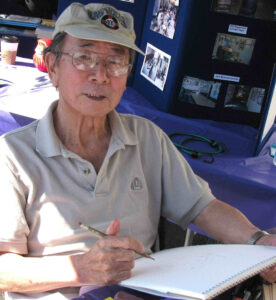 Jack Matsuoka sitting with his sketchbook at a community event in San Jose.