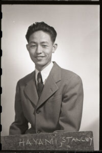 Portrait of Stanley Hayami. He is wearing a suit and smiling at the camera.