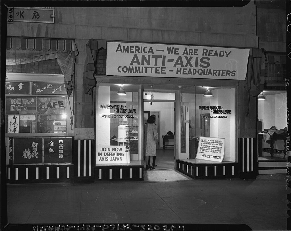 The headquarters of the Anti-Axis Committee in Little Tokyo, December 8, 1941. Signs around the doorway read "America, we are ready. Anti-Axis Committee Headquarters" and "Join now in defeating Axis Japan."
